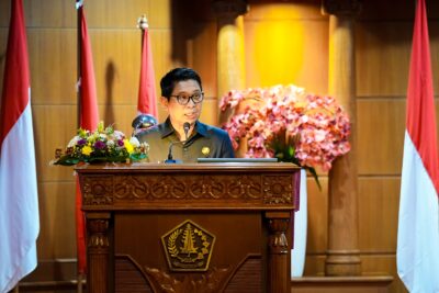 Bupati Badung I Wayan Adi Arnawa menyampaikan penjelasan terhadap Rancangan Peraturan Daerah (Ranperda) tentang Pertanggungjawaban Pelaksanaan APBD Tahun Anggaran 2025 kepada DPRD Kabupaten Badung dalam rapat paripurna, sebagai bentuk pertanggungjawaban pengelolaan keuangan daerah yang telah diaudit Badan Pemeriksa Keuangan (BPK) RI, bertempat di Ruang Sidang Utama Gosana, Gedung DPRD Badung, Senin, (06/07/2026). Rapat paripurna dipimpin Ketua DPRD Badung I Gusti Anom Gumanti, serta dihadiri Wakil Bupati Badung Bagus Alit Sucipta, Pimpinan beserta anggota DPRD Badung, Forkopimda Badung, Sekda Badung IB Surya Suamba serta Pimpinan Perangkat Daerah dilingkungan Pemkab Badung. Dalam penjelasannya, Bupati Adi Arnawa mengatakan, koordinasi Ranperda tersebut merupakan amanat Peraturan Pemerintah Nomor 12 Tahun 2019 dan Peraturan Menteri Dalam Negeri Nomor 77 Tahun 2020 yang mengatur Kepala Daerah wajib menyampaikan pertanggungjawaban pelaksanaan APBD kepada DPRD setelah laporan keuangan diaudit BPK. “Seluruh rangkaian pengelolaan keuangan daerah, mulai dari perencanaan, pelaksanaan, penatausahaan, pelaporan, pertanggungjawaban hingga pengawasan merupakan bagian dari upaya mewujudkan tata kelola pemerintahan yang baik dengan mengedepankan transparansi, akuntabilitas dan partisipatif,” kata Adi Arnawa. Ia menjelaskan pula, Laporan Keuangan Pemerintah Daerah (LKPD) Kabupaten Badung Tahun 2025 kembali memperoleh opini Wajar Tanpa Pengecualian (WTP) dari BPK RI Perwakilan Provinsi Bali. Capaian tersebut menjadi opini WTP ke-14 yang diraih Badung sejak pertama kali diperoleh pada laporan keuangan tahun 2011 serta mempertahankan predikat tersebut selama 12 tahun berturut-turut sejak 2014 hingga 2025. Berdasarkan hasil audit, realisasi pendapatan daerah pada tahun 2025 mencapai Rp. 9,107 triliun atau 81,13 persen dari target sebesar Rp. 11,226 triliun. Pendapatan Asli Daerah (PAD) terealisasi sebesar Rp. 8,063 triliun atau 79,20 persen dari target, sedangkan pendapatan transfer mencapai Rp. 1,043 triliun atau 99,94 persen dari target. Nanti kita memasang target tetap berdasarkan potensi, tapi juga tidak pesimistis. Karena dibalik kita memasang target yang mungkin melebihi realisasi sekarang itu sebagai upaya kita memotivasi Bapenda semakin agresif melakukan pendataan potensi pajak di badung,” terangnya. Sementara itu, realisasi belanja daerah mencapai Rp. 8,301 triliun atau 64,56 persen dari pagu anggaran sebesar Rp. 12,857 triliun. Belanja meliputi belanja operasi Rp. 4,866 triliun, belanja modal Rp. 2,082 triliun, transfer belanja Rp. 1,341 triliun, dan belanja tidak terduga Rp. 10,73 miliar. Dengan capaian tersebut, APBD Kabupaten Badung Tahun Anggaran 2025 mencatat surplus sebesar Rp. 806,53 miliar, berbalik dari target awal yang direncanakan mengalami defisit sebesar Rp 1,63 triliun. Selain itu, Sisa Lebih Pembiayaan Anggaran (SILPA) tercatat sebesar Rp. 1,192 triliun. Adi Arnawa berharap pembahasan Ranperda pertanggungjawaban APBD 2025 dapat berjalan sesuai mekanisme yang berlaku hingga diperoleh persetujuan DPRD. “Kami berharap dokumen pertanggungjawaban pelaksanaan APBD Tahun Anggaran 2025 ini dapat dibahas dan disetujui dalam masa konferensi ini sehingga semakin memperkuat tata kelola pemerintahan yang akuntabel serta memberikan manfaat bagi peningkatan kesejahteraan masyarakat Badung,” ujarnya.