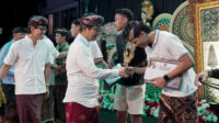 1787462185 Bupati Badung I Wayan Adi Arnawa menghadiri rangkaian Pekan Olahraga dan Seni Desa (Porsenides) Desa Canggu 2026 di Lapangan Desa Canggu, Kecamatan Kuta Utara, Sabtu (22/08/2026). Dalam acara tersebut, Bupati menyaksikan langsung pementasan fragmen tari “Ki Begawan Canggu” yang mengangkat sejarah dan asal-usul desa setempat, sekaligus menyoroti solusi konkret penanganan kemacetan infrastruktur pariwisata. Turut hadir dalam kegiatan tersebut anggota DPRD Badung Made Suryananda Pramana dan I Gede Aryantha, Camat Kuta Utara I Nyoman Tirtayasa beserta jajaran Tripika, Perbekel Canggu I Wayan Suarya, Perbekel Pererenan, perwakilan Perbekel Tibubeneng, Bendesa Adat Canggu I Nyoman Siana, serta para tokoh adat, dinas, dan masyarakat Canggu. Bupati Adi Arnawa memberikan apresiasi tinggi terhadap karya seni tersebut sebagai langkah strategis memperkuat identitas budaya dan mendukung pariwisata berbasis budaya yang autentik. “Fragmen tari ini bukan sekadar pertunjukan, tetapi menjadi medium untuk menjaga memori kolektif, nilai budaya, dan jati diri masyarakat. Ketika sejarah dan budaya dikemas secara kreatif, desa dapat memperkuat daya saing destinasi dan menghadirkan pengalaman wisata yang autentik,” kata Adi Arnawa. Di tengah pesatnya pertumbuhan pariwisata Canggu, Bupati Adi Arnawa secara terbuka menyoroti persoalan krusial berupa kemacetan akut dan tingginya tekanan terhadap kapasitas infrastruktur transportasi, khususnya di kawasan Canggu dan Tibubeneng. Ia menegaskan mobilitas yang terhambat dapat menurunkan kenyamanan wisatawan dan merusak daya saing destinasi. Sebagai solusi nyata, Pemkab Badung saat ini tengah menggenjot pembangunan jalur konektivitas alternatif. Jalur ini akan menghubungkan kawasan Canggu-Berawa-Banjar Umalas-Seminyak-Kedampang hingga ke Teuku Umar Barat dengan total panjang sekitar 4,7 kilometer. “Untuk tahap awal 2026, kami berharap ruas sepanjang 4,7 kilometer ini dapat diselesaikan pada akhir Desember nanti. Infrastruktur ini diharapkan mampu mendistribusikan arus lalu lintas secara optimal dan memecah konsentrasi kendaraan di Canggu serta Tibubeneng,” jelasnya. Tidak berhenti di sana, Pemkab Badung juga memproyeksikan pembangunan jalan pintas (shortcut) dari kawasan Gatot Subroto Barat pada tahun anggaran 2027–2028 sebagai langkah jangka panjang. “Jangan sampai destinasi yang sangat diminati justru menghadapi kejenuhan akibat persoalan mobilitas. Kekuatan pariwisata Bali bukan hanya soal fasilitas dan keindahan alam, tetapi juga kemampuan masyarakat menjaga dan mengembangkan identitas budayanya,” tegas Bupati Adi Arnawa. Pada kesempatan tersebut Bupati menyerahkan hadiah kepada para pemenang turnamen bola voli Porsenides Desa Canggu 2026. Dalam kompetisi tersebut, Tim Porba Banjar Babakan sukses keluar sebagai juara pertama. Posisi juara kedua diraih oleh tim Macan Canggu, disusul oleh tim Putra Roket Banjar Tegal Gundul yang mengamankan tempat ketiga.
