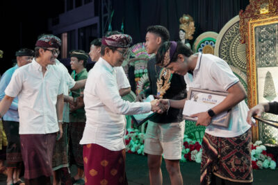 Bupati Badung I Wayan Adi Arnawa menghadiri rangkaian Pekan Olahraga dan Seni Desa (Porsenides) Desa Canggu 2026 di Lapangan Desa Canggu, Kecamatan Kuta Utara, Sabtu (22/08/2026). Dalam acara tersebut, Bupati menyaksikan langsung pementasan fragmen tari “Ki Begawan Canggu” yang mengangkat sejarah dan asal-usul desa setempat, sekaligus menyoroti solusi konkret penanganan kemacetan infrastruktur pariwisata. Turut hadir dalam kegiatan tersebut anggota DPRD Badung Made Suryananda Pramana dan I Gede Aryantha, Camat Kuta Utara I Nyoman Tirtayasa beserta jajaran Tripika, Perbekel Canggu I Wayan Suarya, Perbekel Pererenan, perwakilan Perbekel Tibubeneng, Bendesa Adat Canggu I Nyoman Siana, serta para tokoh adat, dinas, dan masyarakat Canggu. Bupati Adi Arnawa memberikan apresiasi tinggi terhadap karya seni tersebut sebagai langkah strategis memperkuat identitas budaya dan mendukung pariwisata berbasis budaya yang autentik. “Fragmen tari ini bukan sekadar pertunjukan, tetapi menjadi medium untuk menjaga memori kolektif, nilai budaya, dan jati diri masyarakat. Ketika sejarah dan budaya dikemas secara kreatif, desa dapat memperkuat daya saing destinasi dan menghadirkan pengalaman wisata yang autentik,” kata Adi Arnawa. Di tengah pesatnya pertumbuhan pariwisata Canggu, Bupati Adi Arnawa secara terbuka menyoroti persoalan krusial berupa kemacetan akut dan tingginya tekanan terhadap kapasitas infrastruktur transportasi, khususnya di kawasan Canggu dan Tibubeneng. Ia menegaskan mobilitas yang terhambat dapat menurunkan kenyamanan wisatawan dan merusak daya saing destinasi. Sebagai solusi nyata, Pemkab Badung saat ini tengah menggenjot pembangunan jalur konektivitas alternatif. Jalur ini akan menghubungkan kawasan Canggu-Berawa-Banjar Umalas-Seminyak-Kedampang hingga ke Teuku Umar Barat dengan total panjang sekitar 4,7 kilometer. “Untuk tahap awal 2026, kami berharap ruas sepanjang 4,7 kilometer ini dapat diselesaikan pada akhir Desember nanti. Infrastruktur ini diharapkan mampu mendistribusikan arus lalu lintas secara optimal dan memecah konsentrasi kendaraan di Canggu serta Tibubeneng,” jelasnya. Tidak berhenti di sana, Pemkab Badung juga memproyeksikan pembangunan jalan pintas (shortcut) dari kawasan Gatot Subroto Barat pada tahun anggaran 2027–2028 sebagai langkah jangka panjang. “Jangan sampai destinasi yang sangat diminati justru menghadapi kejenuhan akibat persoalan mobilitas. Kekuatan pariwisata Bali bukan hanya soal fasilitas dan keindahan alam, tetapi juga kemampuan masyarakat menjaga dan mengembangkan identitas budayanya,” tegas Bupati Adi Arnawa. Pada kesempatan tersebut Bupati menyerahkan hadiah kepada para pemenang turnamen bola voli Porsenides Desa Canggu 2026. Dalam kompetisi tersebut, Tim Porba Banjar Babakan sukses keluar sebagai juara pertama. Posisi juara kedua diraih oleh tim Macan Canggu, disusul oleh tim Putra Roket Banjar Tegal Gundul yang mengamankan tempat ketiga.